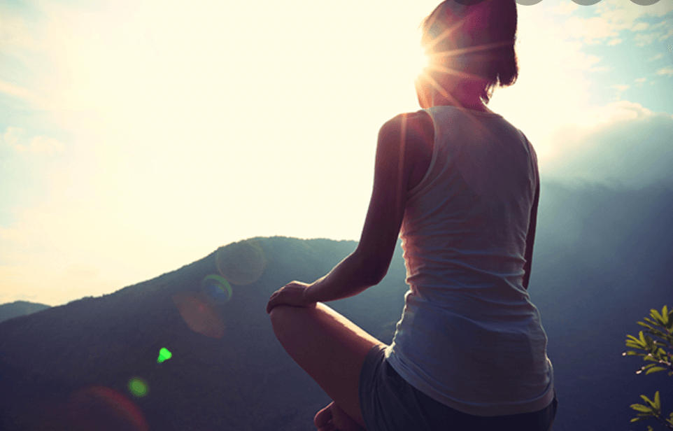 A woman meditating in the mountains.