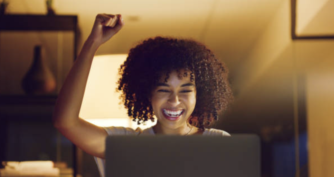 Happy woman sitting behind a laptop computer.