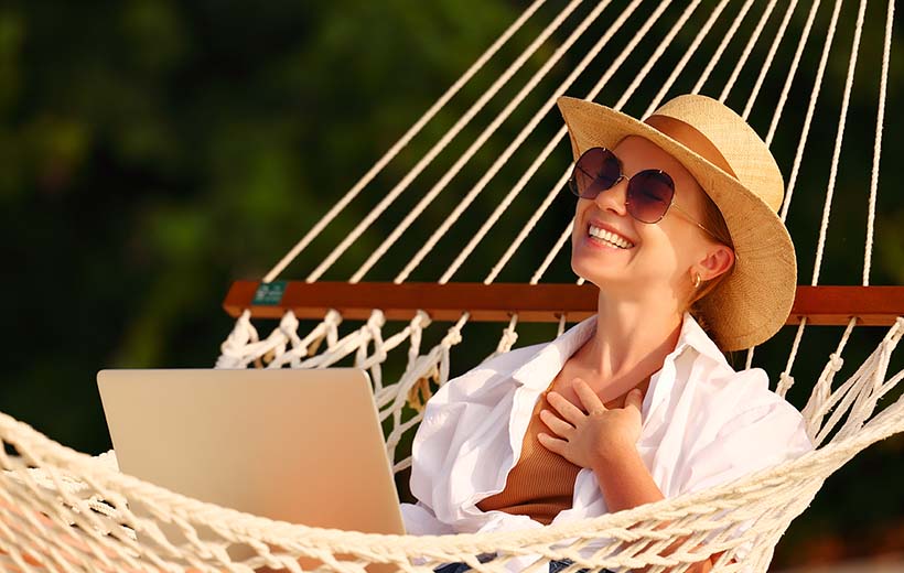 happy woman in a hammock smiling at a laptop computer