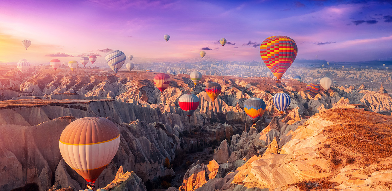 Aerial view amazing sunrise landscape in Cappadocia with colorful hot air balloon fly in sky over deep canyons, valleys. Concept banner travel Turkey.