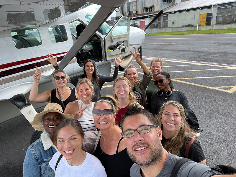 A group shot of an earlier retreat standing in front of the prop plane they traveled in.